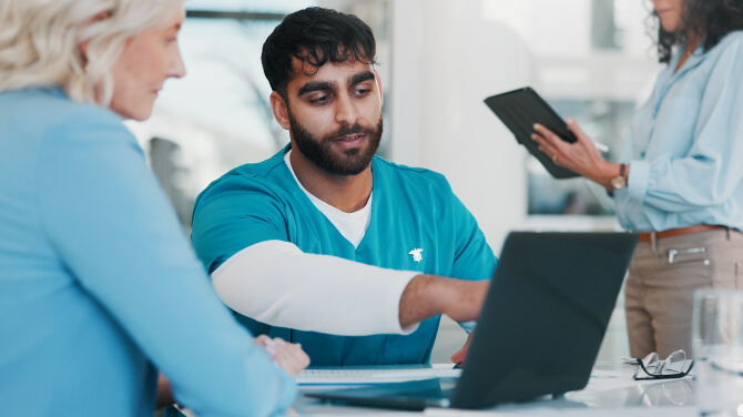 A physician sits at a table with two fellow physicians, discussing reimbursement challenges in healthcare today.