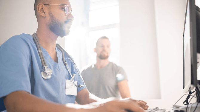 A physician utilizes a computer to demonstrate the capabilities of the athenaOne® Advanced Intelligence Layer.