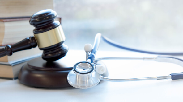 A stethoscope resting next to a gavel and legal books, symbolizing the intersection of medicine and law.