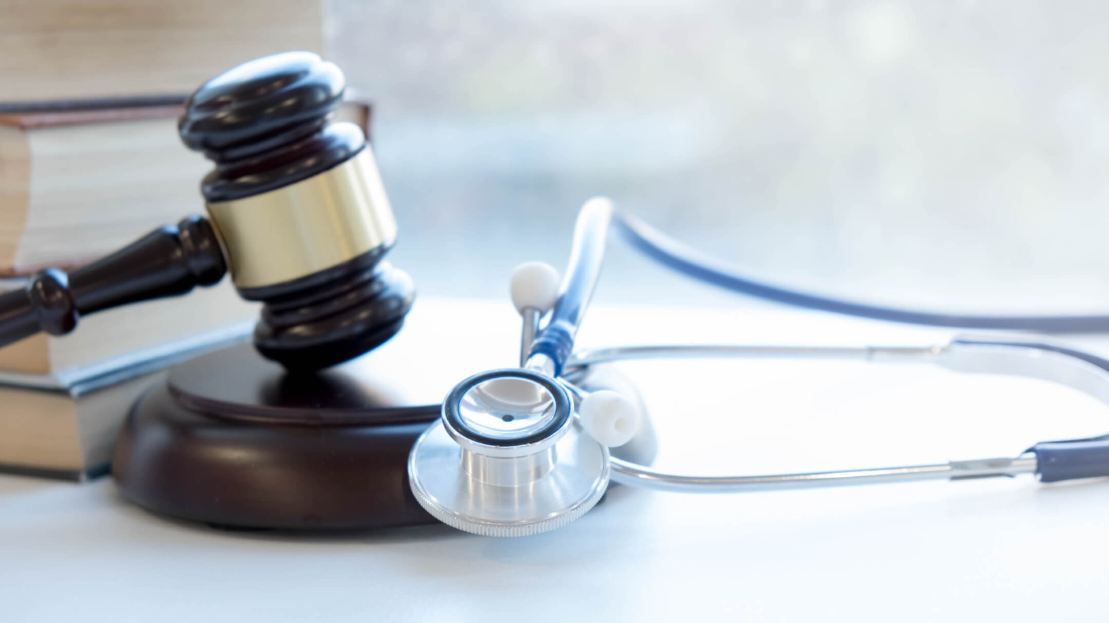 A stethoscope resting next to a gavel and legal books, symbolizing the intersection of medicine and law.