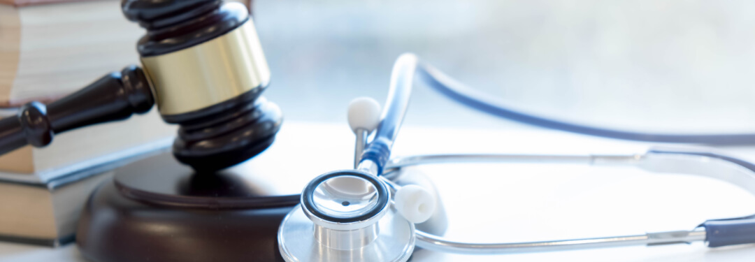 A stethoscope resting next to a gavel and legal books, symbolizing the intersection of medicine and law.