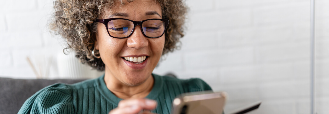 A patient smiles as she successfully contacts her doctor’s office using a patient portal on her mobile phone.