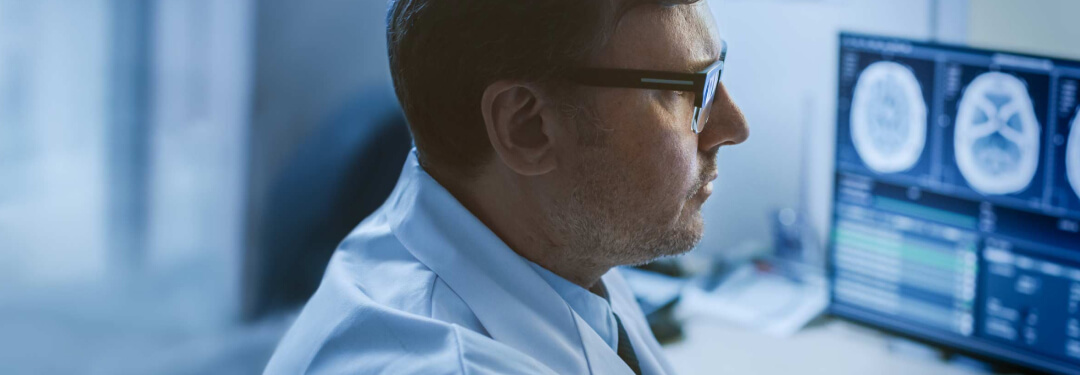 Doctor with glasses looks at a patient chart in the EHR.