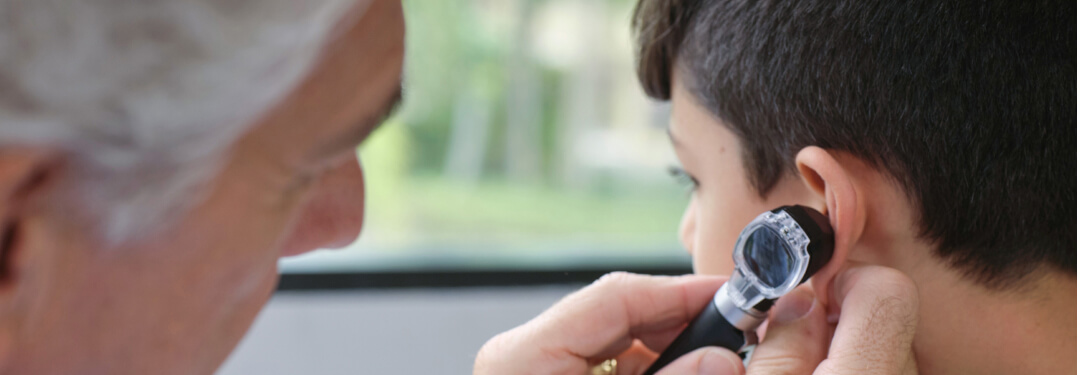 A doctor examines a patient's ear, showcasing pediatric care and clinical efficiency at Mali & Mali Pediatrics with athenaOne.