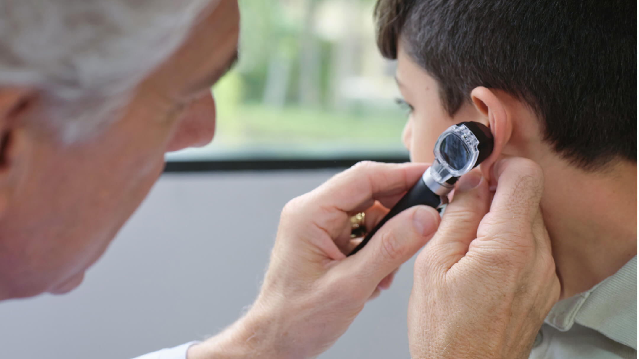 A doctor examines a patient's ear, showcasing pediatric care and clinical efficiency at Mali & Mali Pediatrics with athenaOne.