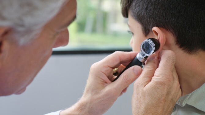 A doctor examines a patient's ear, showcasing pediatric care and clinical efficiency at Mali & Mali Pediatrics with athenaOne.