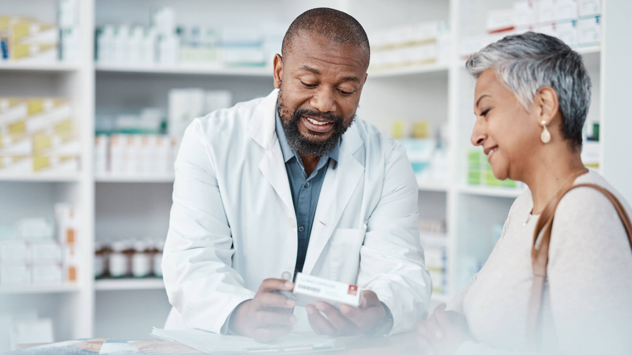 A man and a woman are standing in a pharmacy, examining the directions of a prescription together.