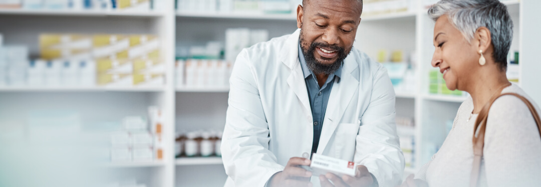 A man and a woman are standing in a pharmacy, examining the directions of a prescription together.