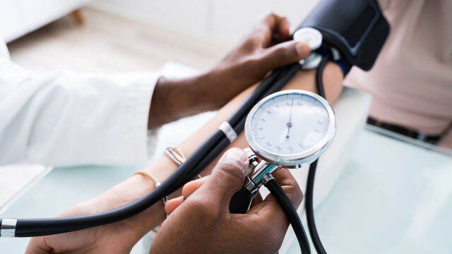 doctors hands shown taking the blood pressure of a patient 