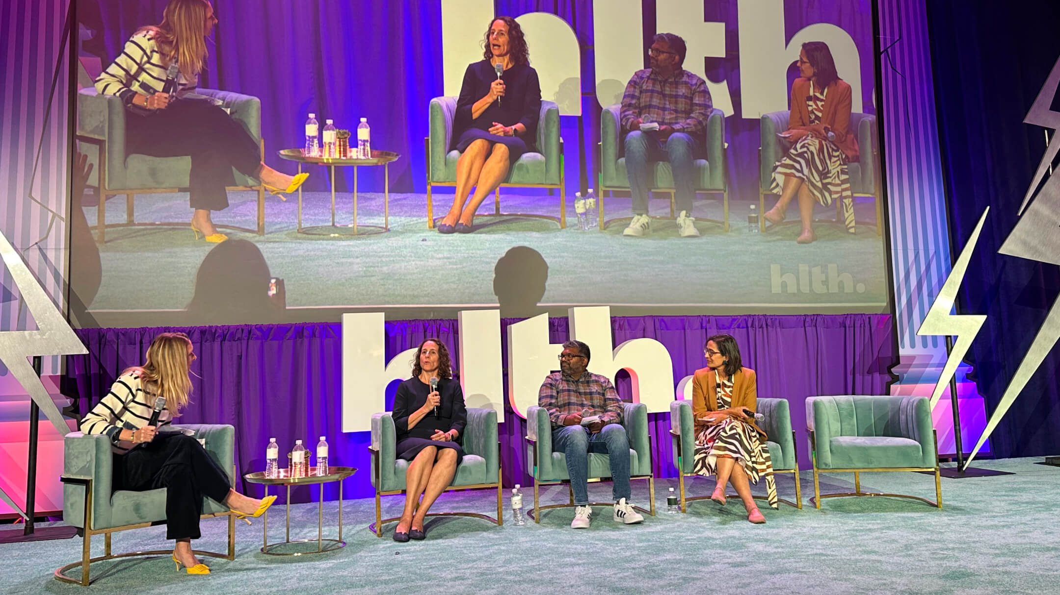 A panel of people sitting on stage discussing the theme of scaling advanced primary care through technology.