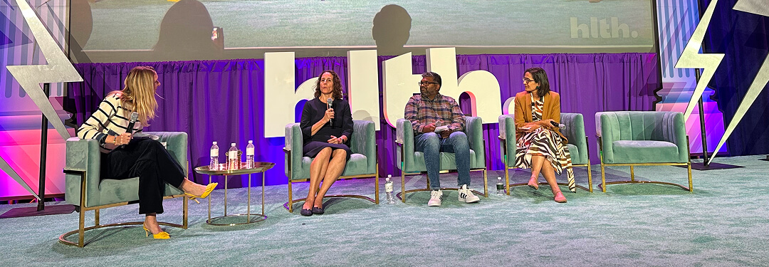 A panel of people sitting on stage discussing the theme of scaling advanced primary care through technology.