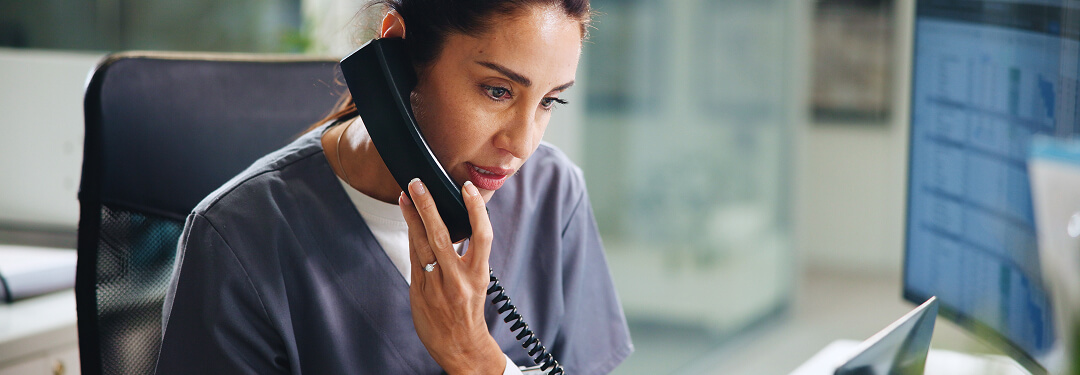 A physician in scrubs speaks on the phone, emphasizing the importance of efficient EHR systems for faster payments and smarter work.