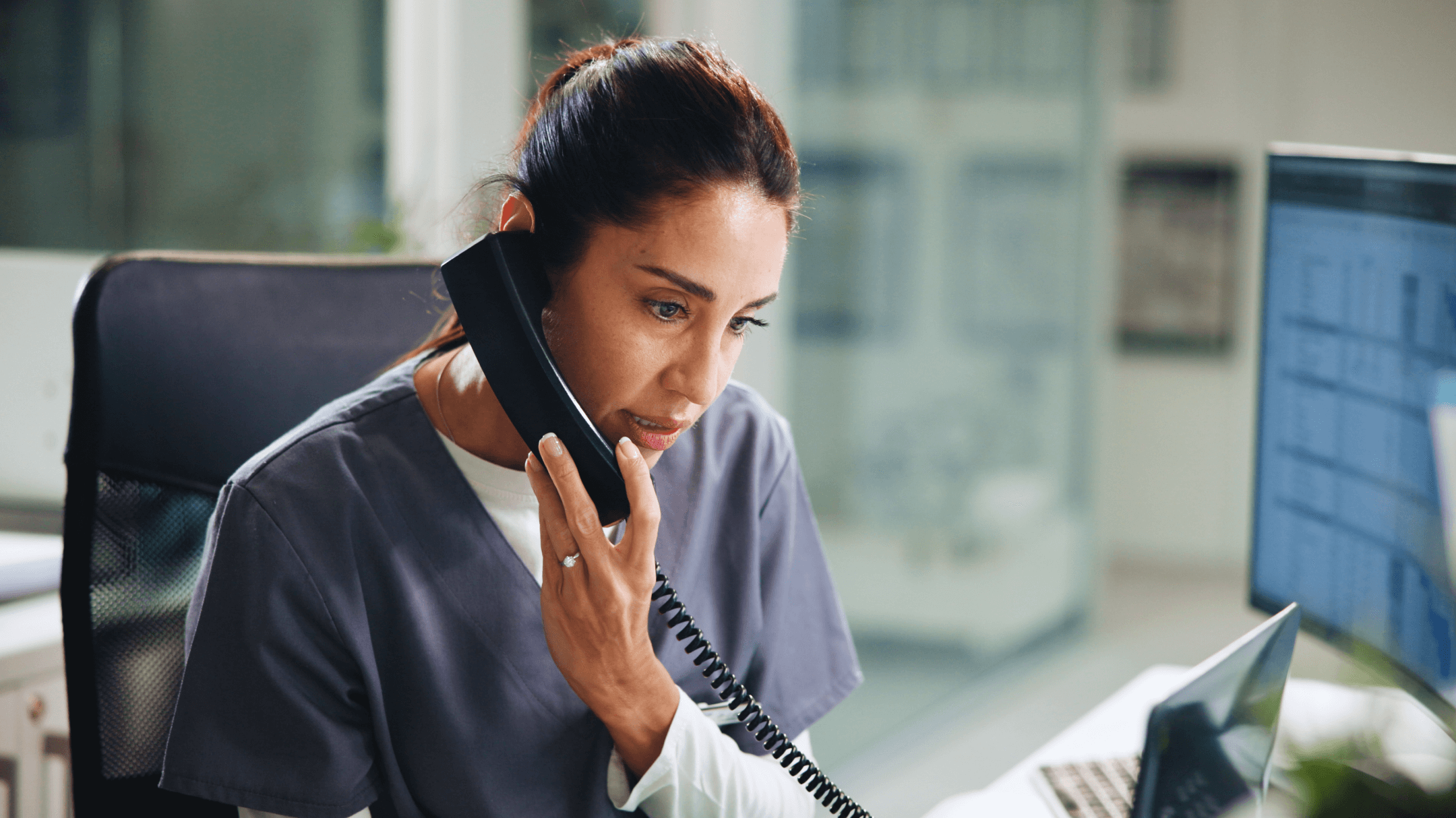A physician in scrubs speaks on the phone, emphasizing the importance of efficient EHR systems for faster payments and smarter work.