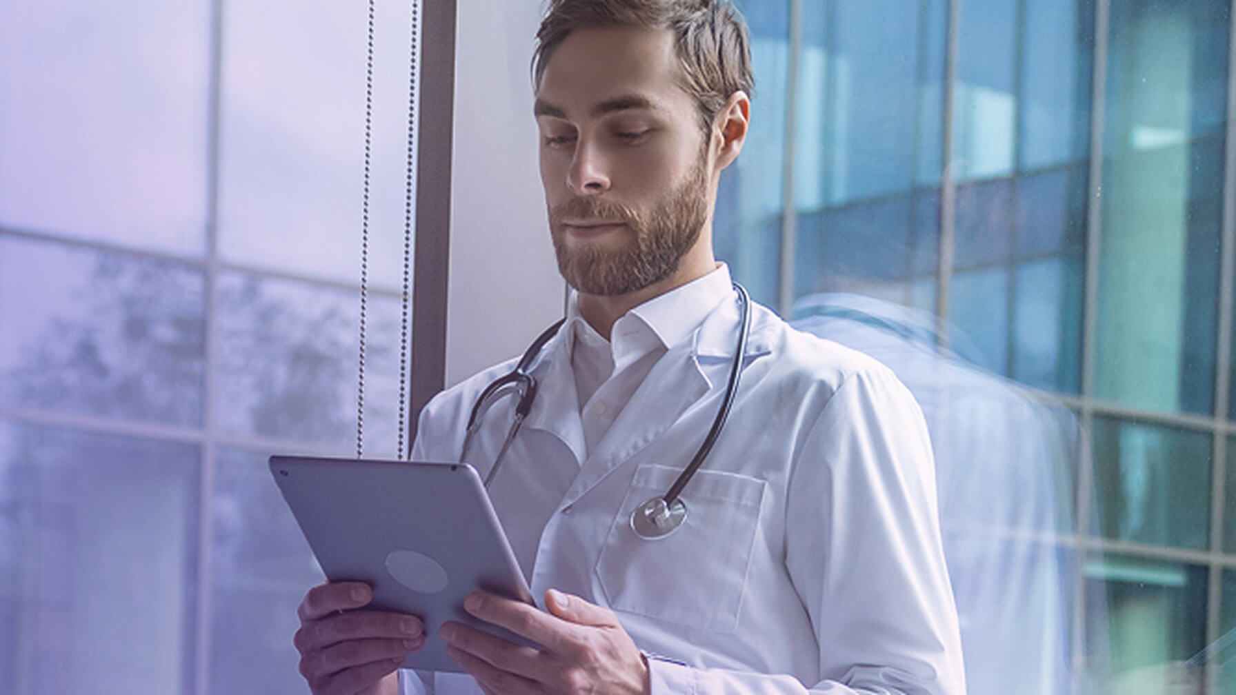 Physician standing in a clinical setting working on a tablet with AI tools.