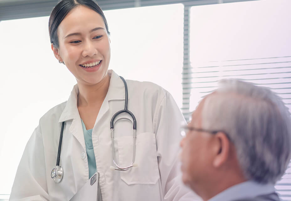 Clinician smiling down at patient while checking vitals