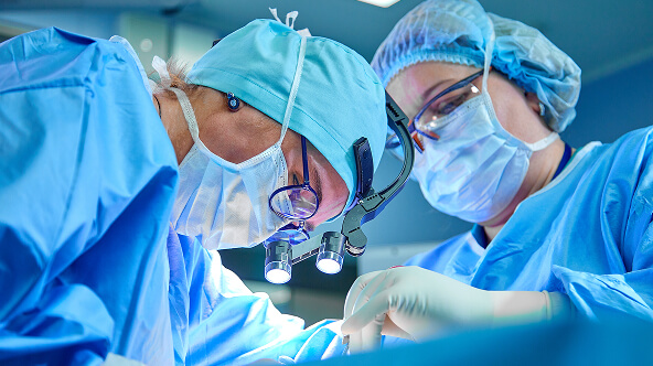 Two physicians in surgical gear inside a pain management ASC operating room.