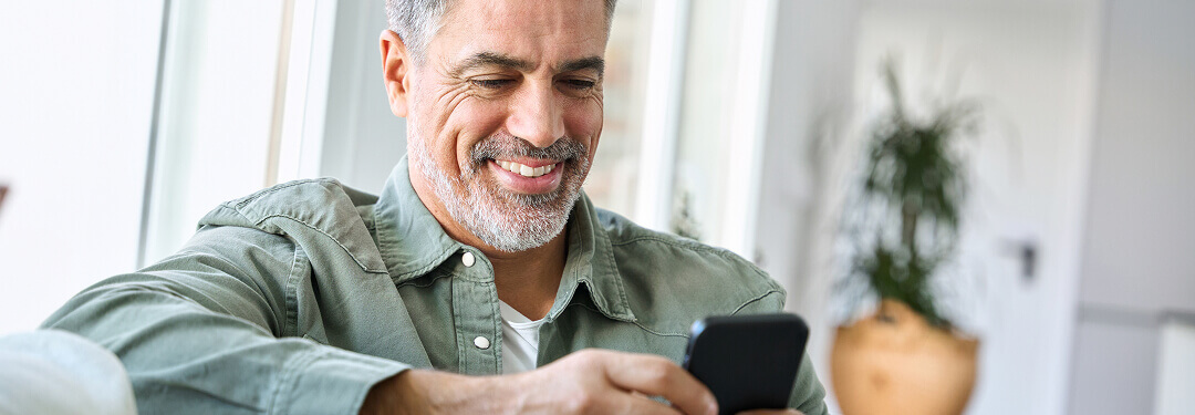 Patient smiling reading a care update received in their multilingual patient portal.