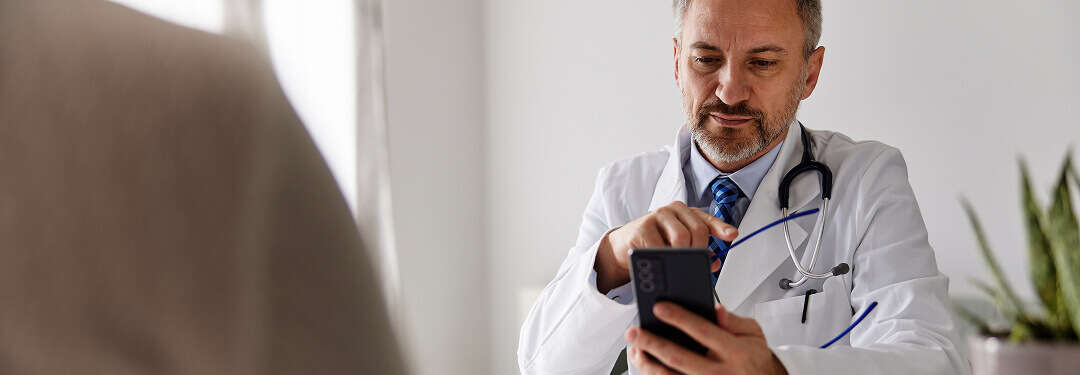 A physician checks a cell phone, highlighting advancements in patient data privacy with athenaOne®.