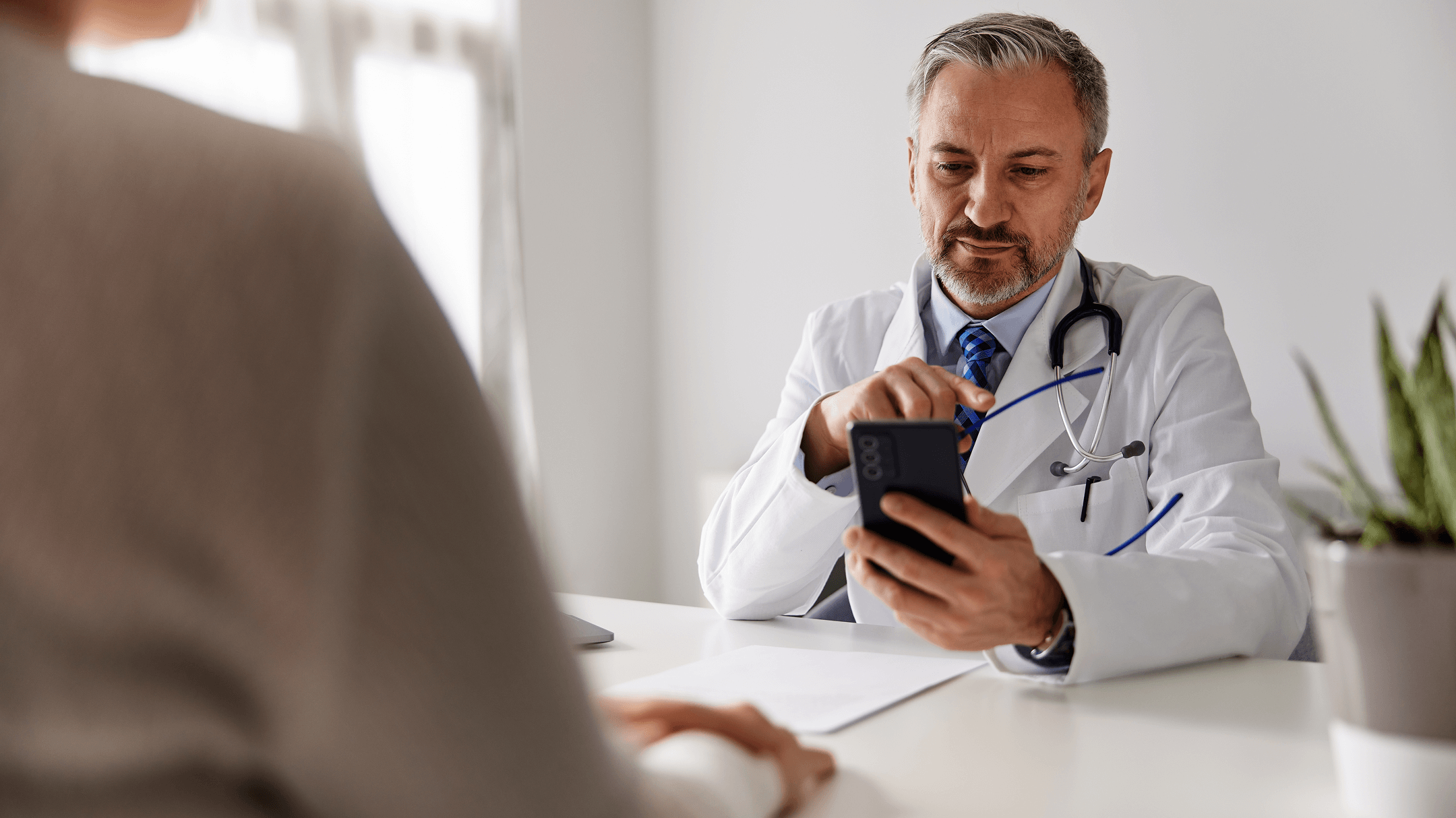 A physician checks a cell phone, highlighting advancements in patient data privacy with athenaOne®.