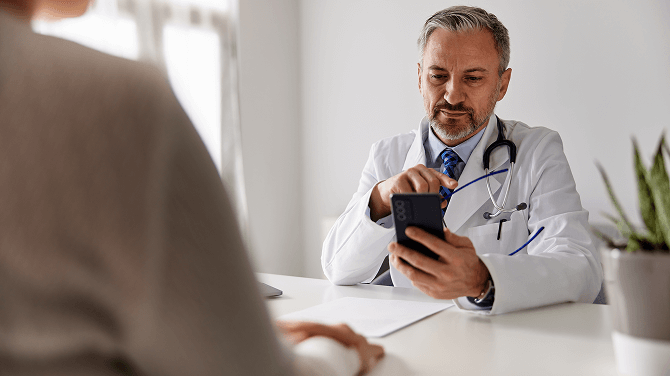 A physician checks a cell phone, highlighting advancements in patient data privacy with athenaOne®.