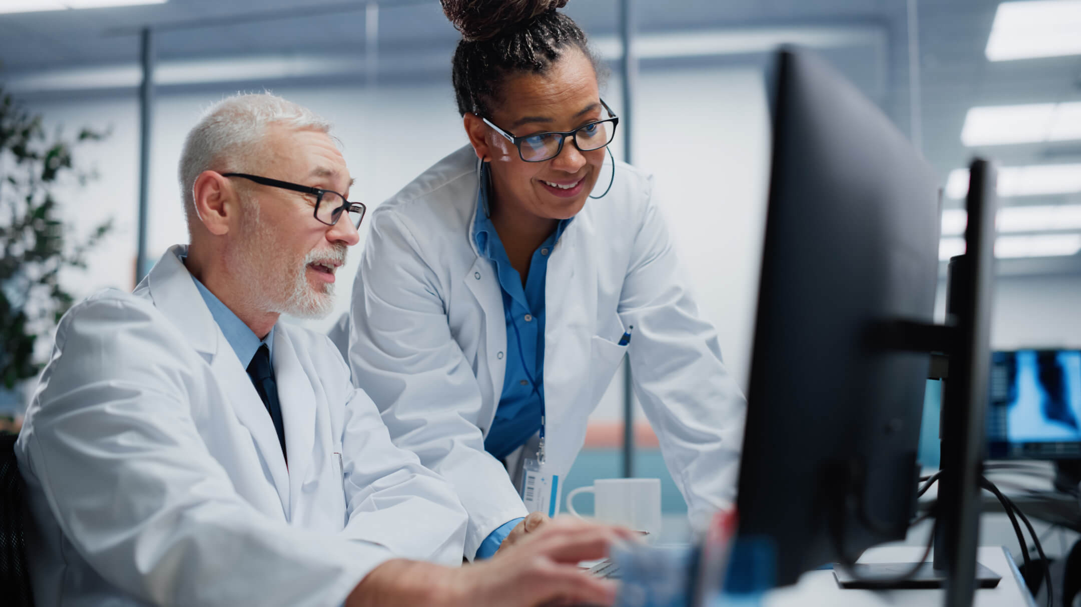 Two doctors are analyzing a computer screen focused on best practices for generative AI in clinical documentation.