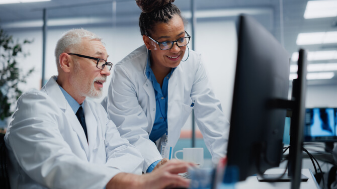 Two doctors are analyzing a computer screen focused on best practices for generative AI in clinical documentation.