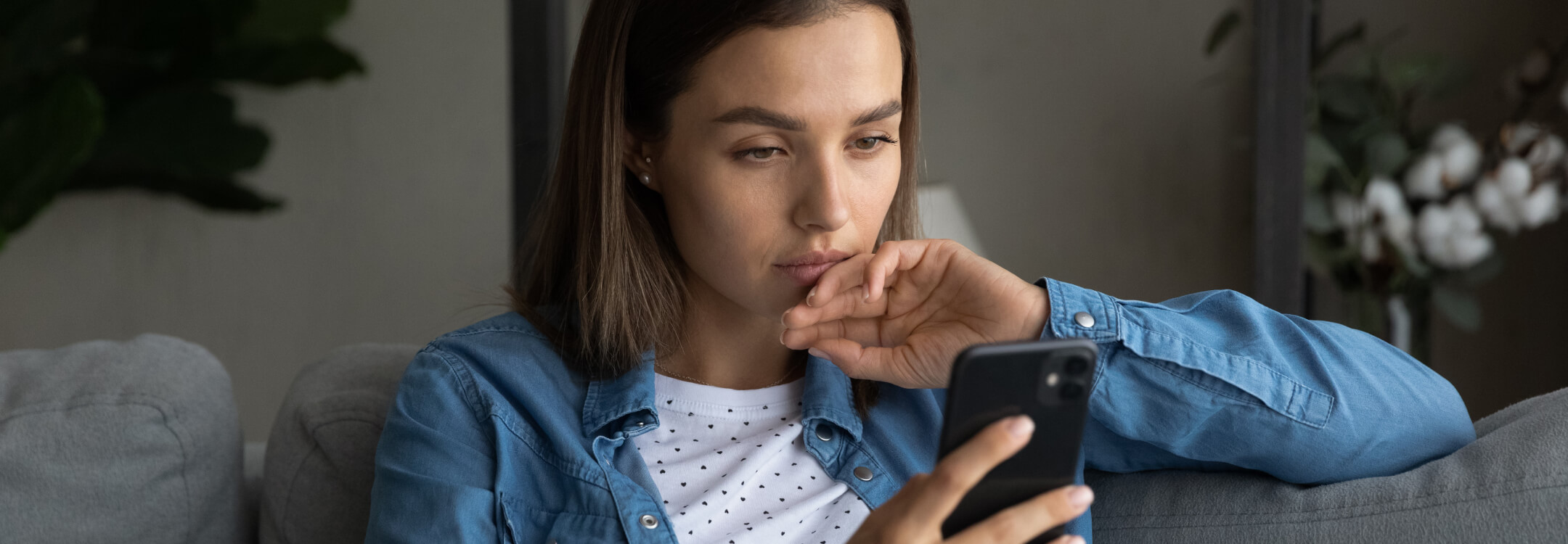 A patient on a couch engages with her phone, contemplating 2025 healthcare predictions.
