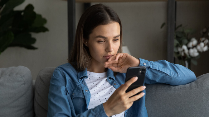 A patient on a couch engages with her phone, contemplating 2025 healthcare predictions.