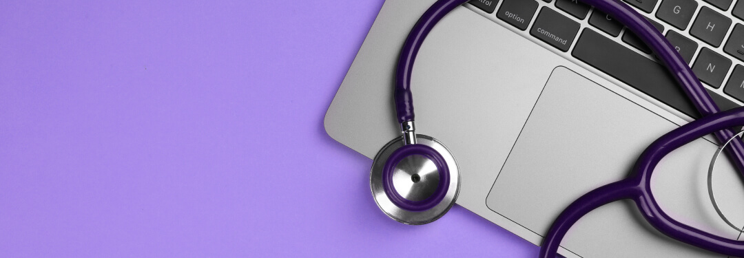 On a purple background, a laptop and a stethoscope are displayed.