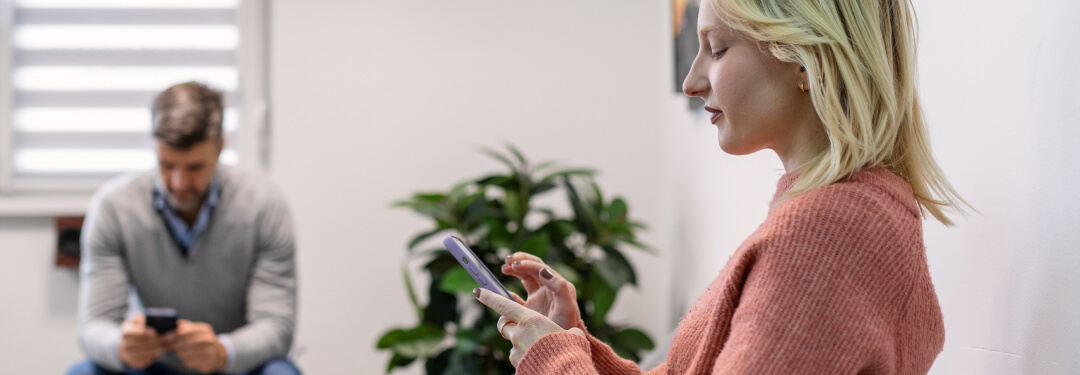 Woman using a digital check-in tool while in the waiting room of a doctor’s office.