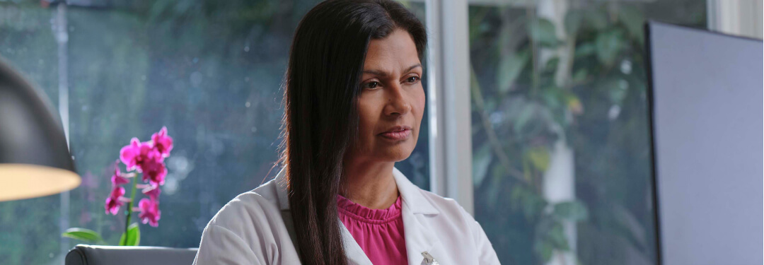 A physician sits at their desk, working on their computer.