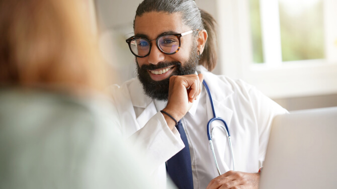  A healthcare professional smiling while discussing value-based care with a patient using athenaOne.