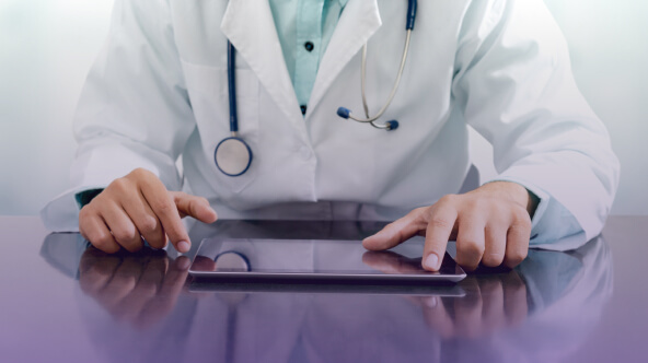 A healthcare professional uses a tablet to access medical data their office.