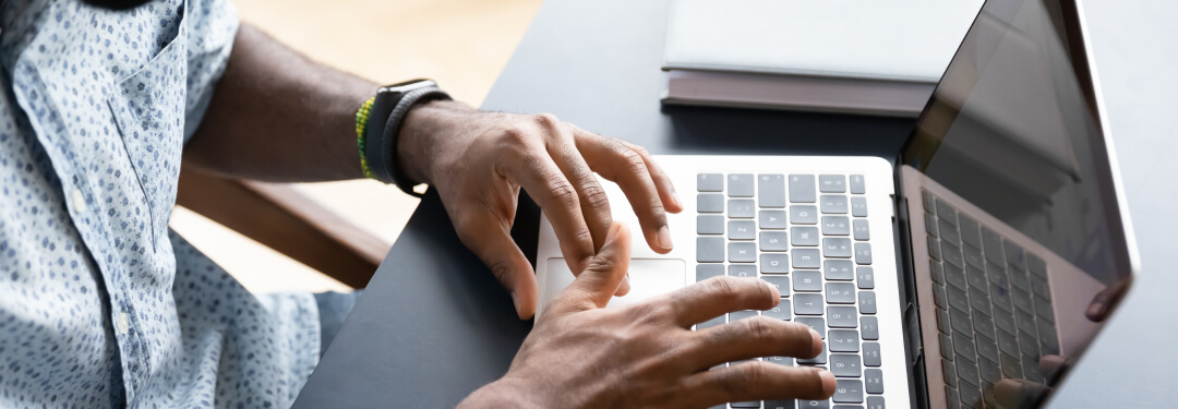 A persons hands on a laptop keyboard