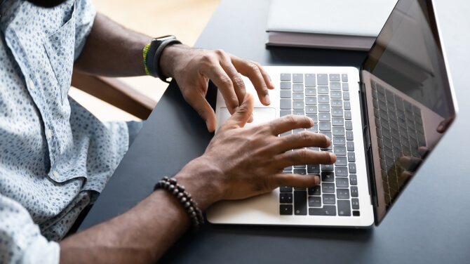 A persons hands on a laptop keyboard