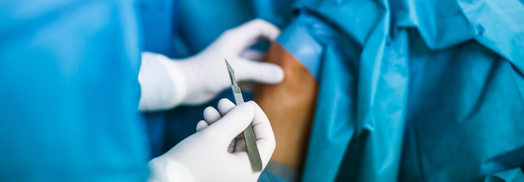 A healthcare professional in blue scrubs is holding scissors, highlighting key orthopedic surgery trends.