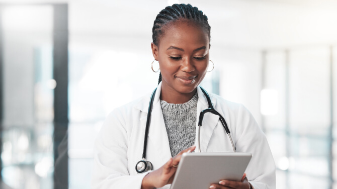 A doctor is holding a tablet, which reflects the diverse views on AI in healthcare research in the U.S.