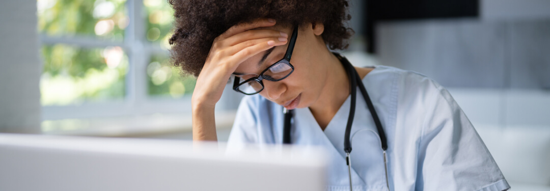 physician with head down working on health records