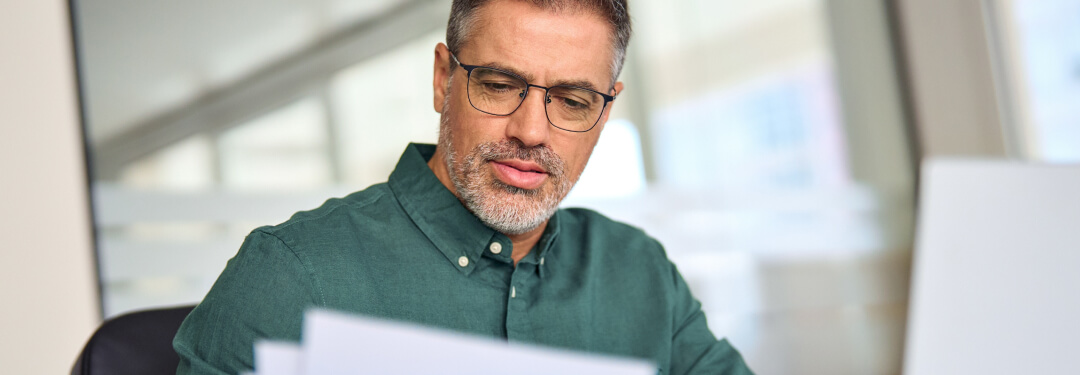 A man examines papers and his laptop to get more information on fee schedules.