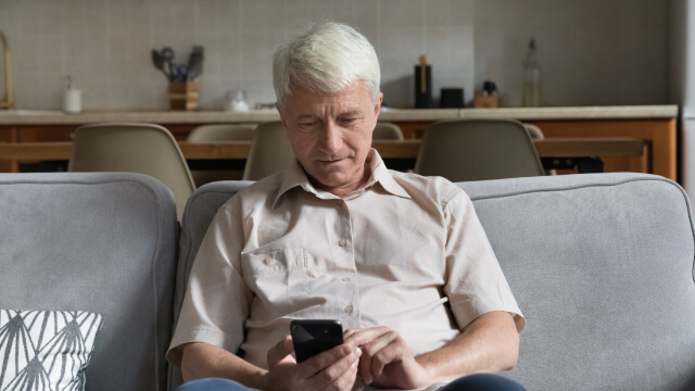 Senior citizen engaged in self check-in using mobile device.