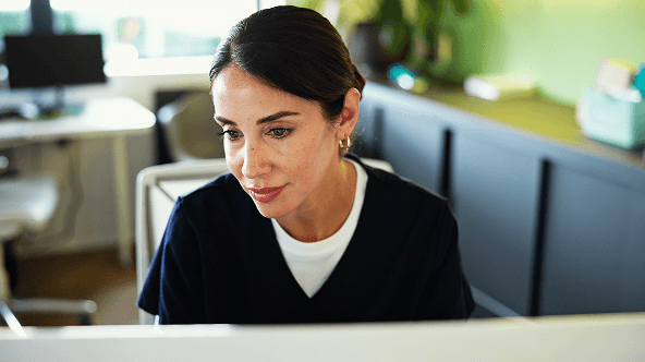Woman in scrubs at computer.