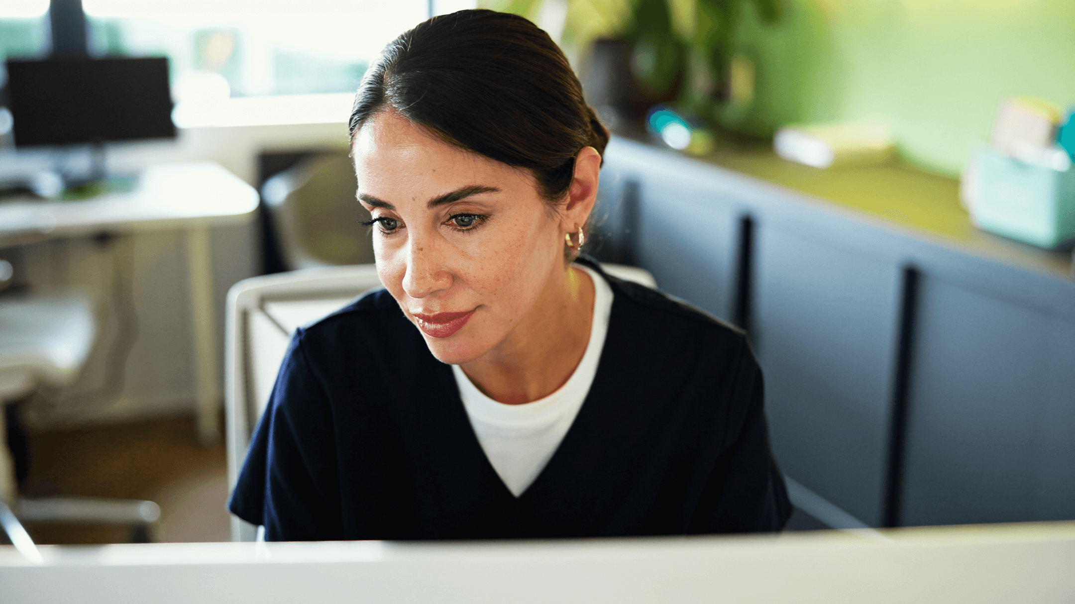 Woman in scrubs at computer.
