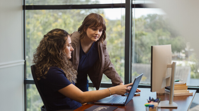 Two practice administrators read AI-powered clinical notes uploaded to the patient chart.