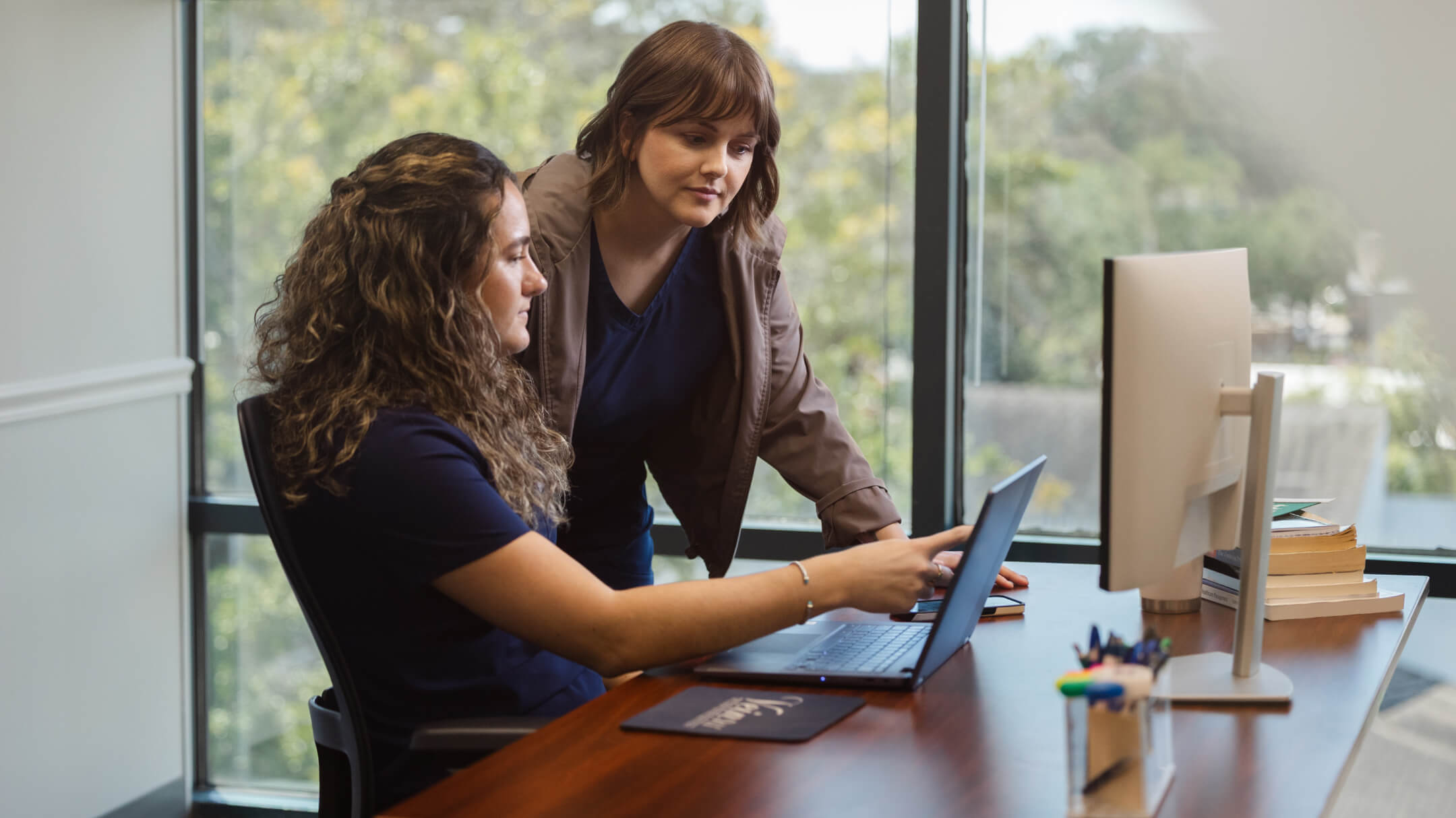 Two practice administrators read AI-powered clinical notes uploaded to the patient chart.