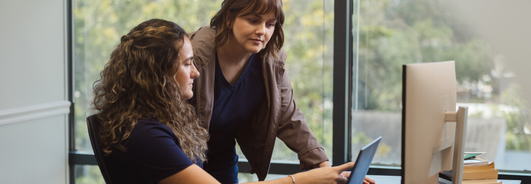 Two practice administrators read AI-powered clinical notes uploaded to the patient chart.