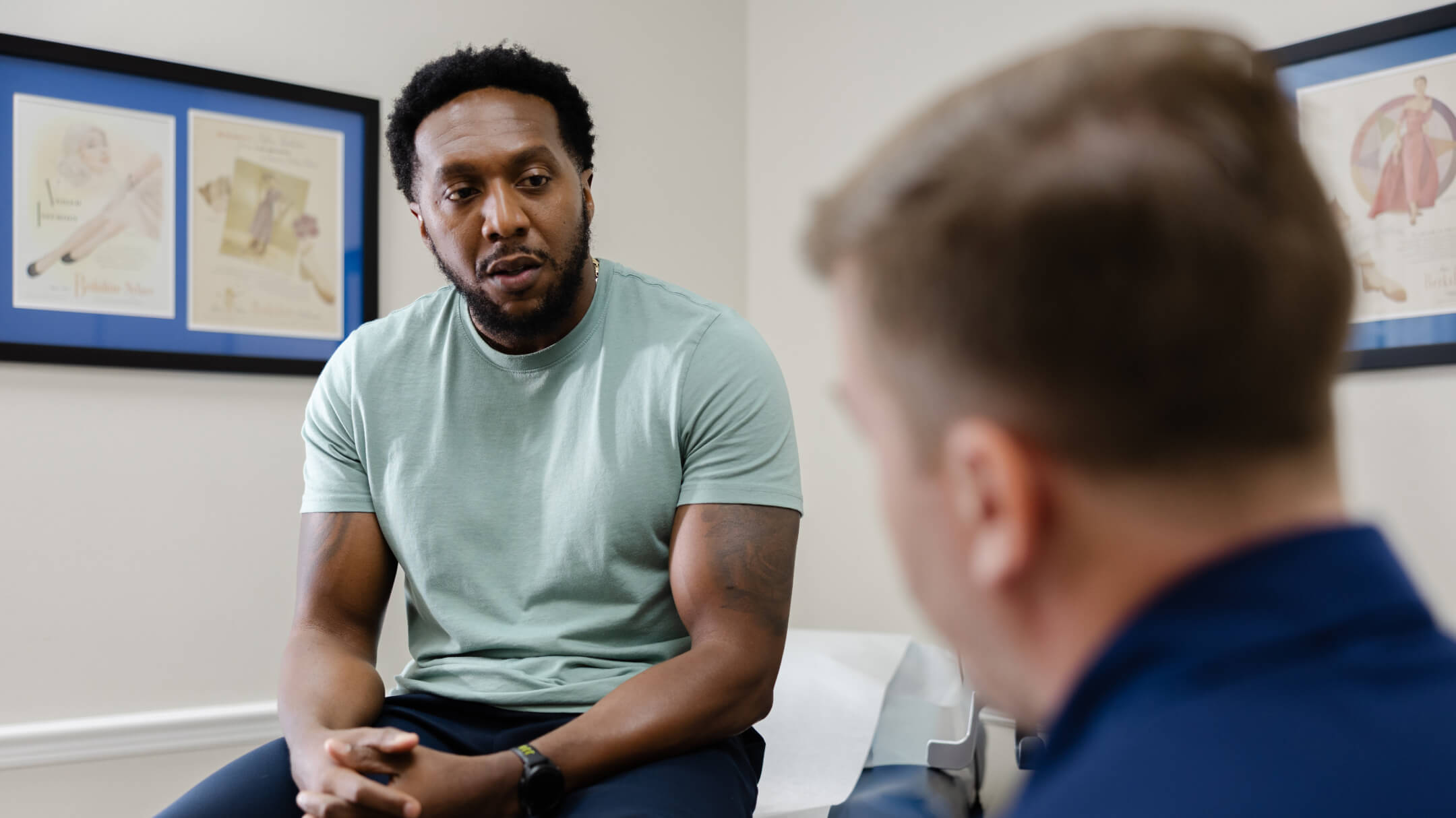 A seated patient talks with the physician, focusing on new athenaOne® features and AI advancements for fall 2025.