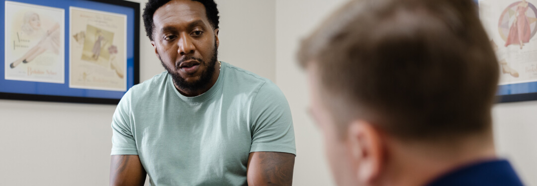 A seated patient talks with the physician, focusing on new athenaOne® features and AI advancements for fall 2025.