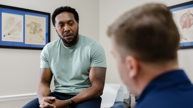 A seated patient talks with the physician, focusing on new athenaOne® features and AI advancements for fall 2025.