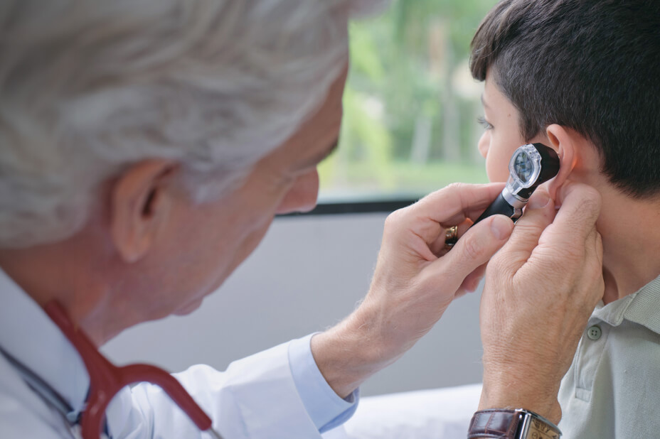 Physician examines a young patients ear with medical device
