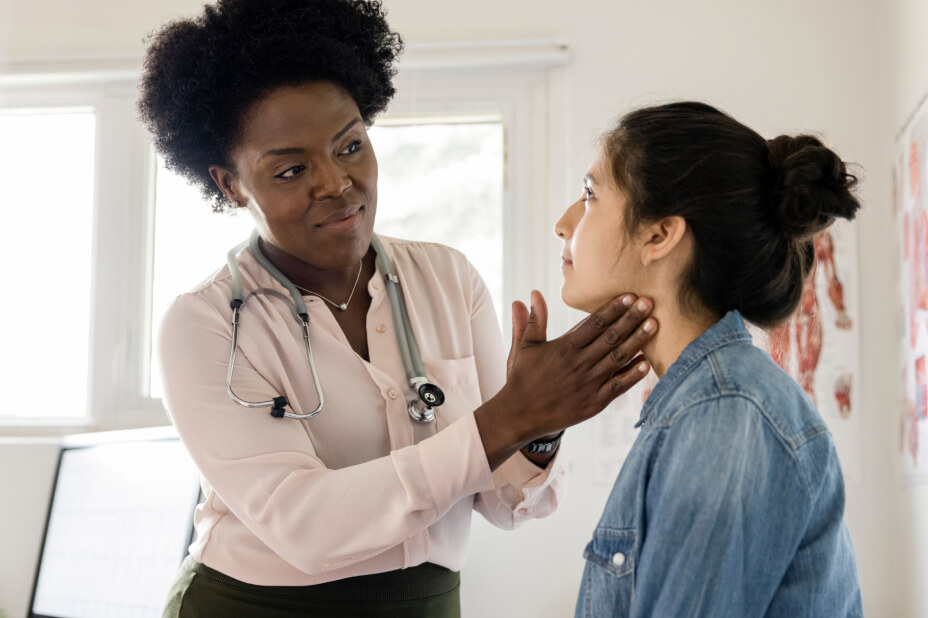 A medical professional wearing a stethoscope examines a patients through with her hands